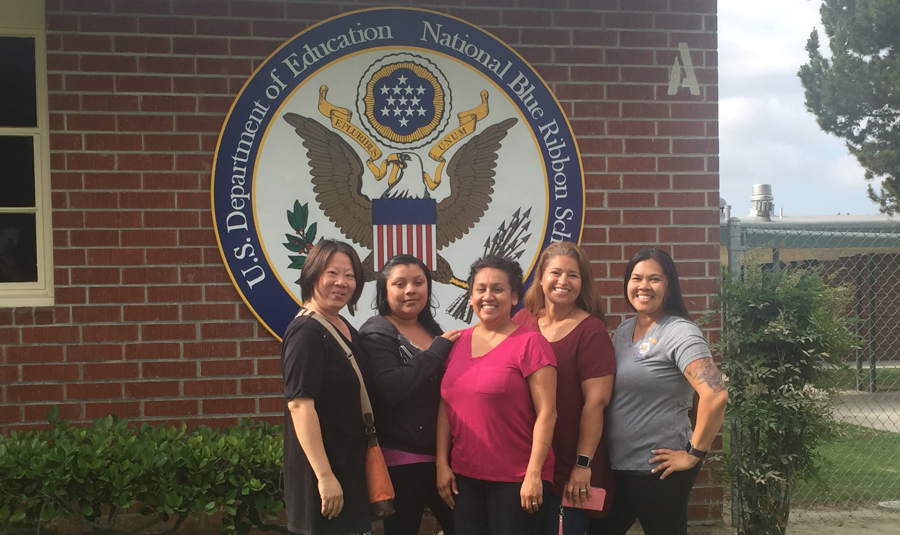 Volunteer mothers pose in front of the school's new badge of honor: The National Blue Ribbon!