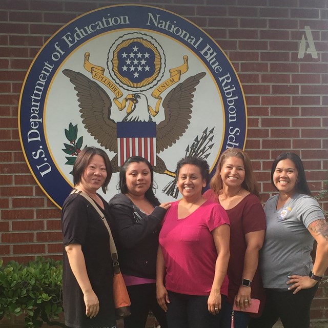 Volunteer mothers pose in front of the school's new badge of honor: The National Blue Ribbon!